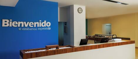 A reception desk with a blue wall and a clock.
