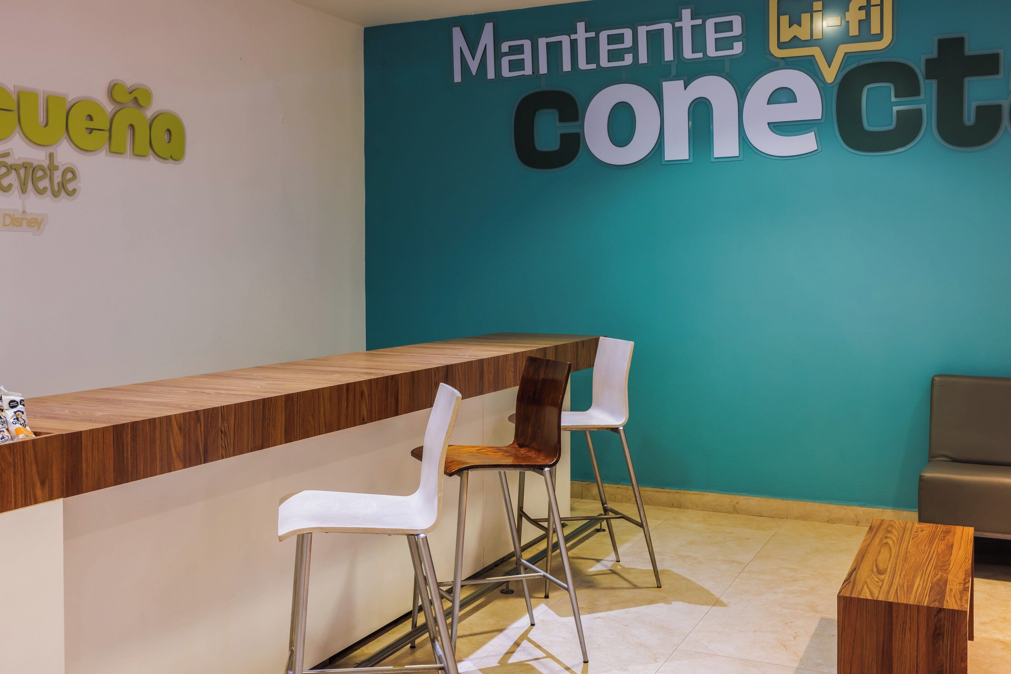 A reception desk with two chairs, a wooden counter, and a teal wall with signage.