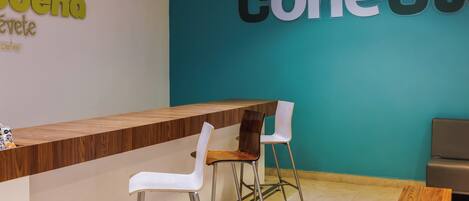 A reception desk with two chairs, a wooden counter, and a teal wall with signage.