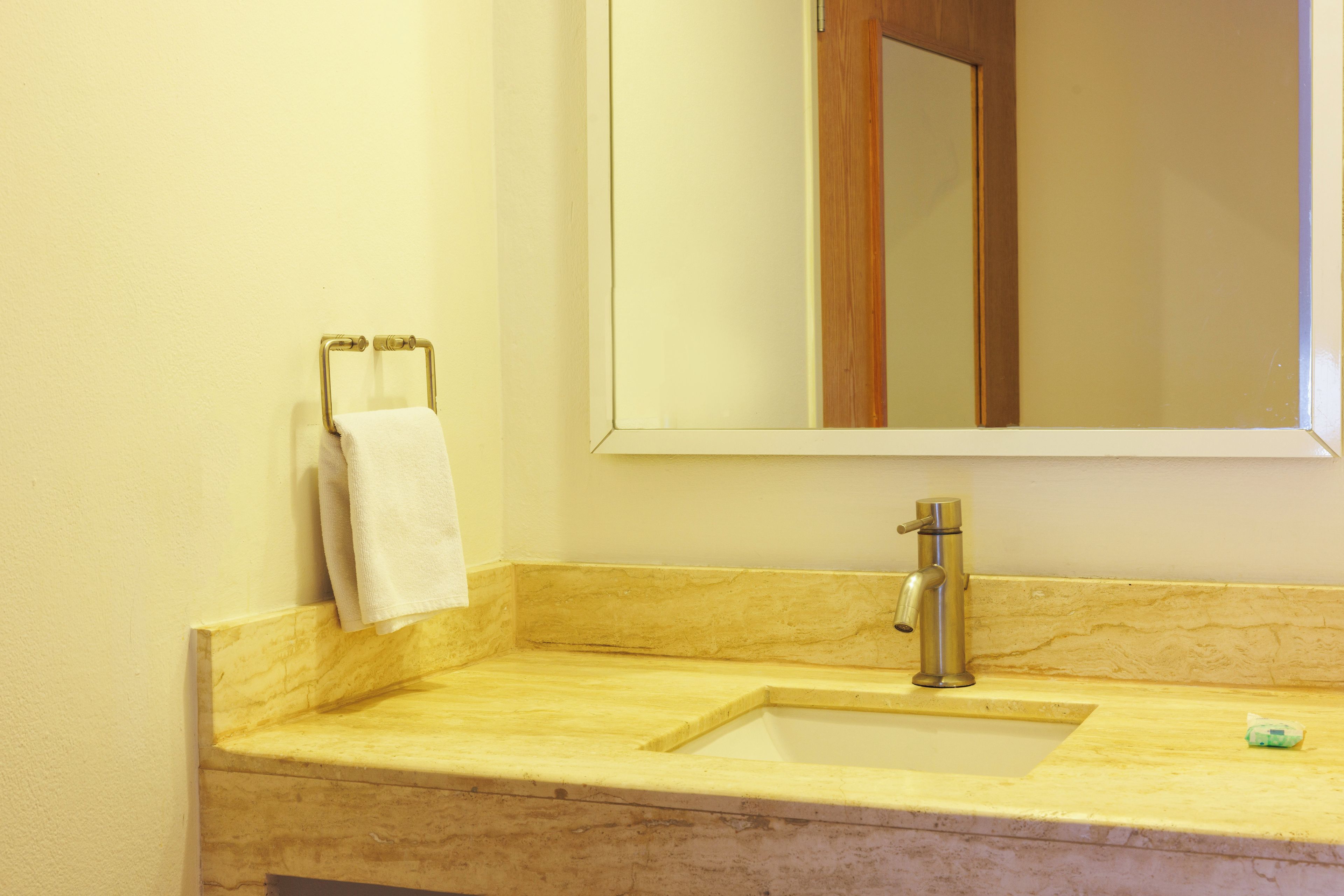 A bathroom with a marble sink, a mirror, and a towel rack.