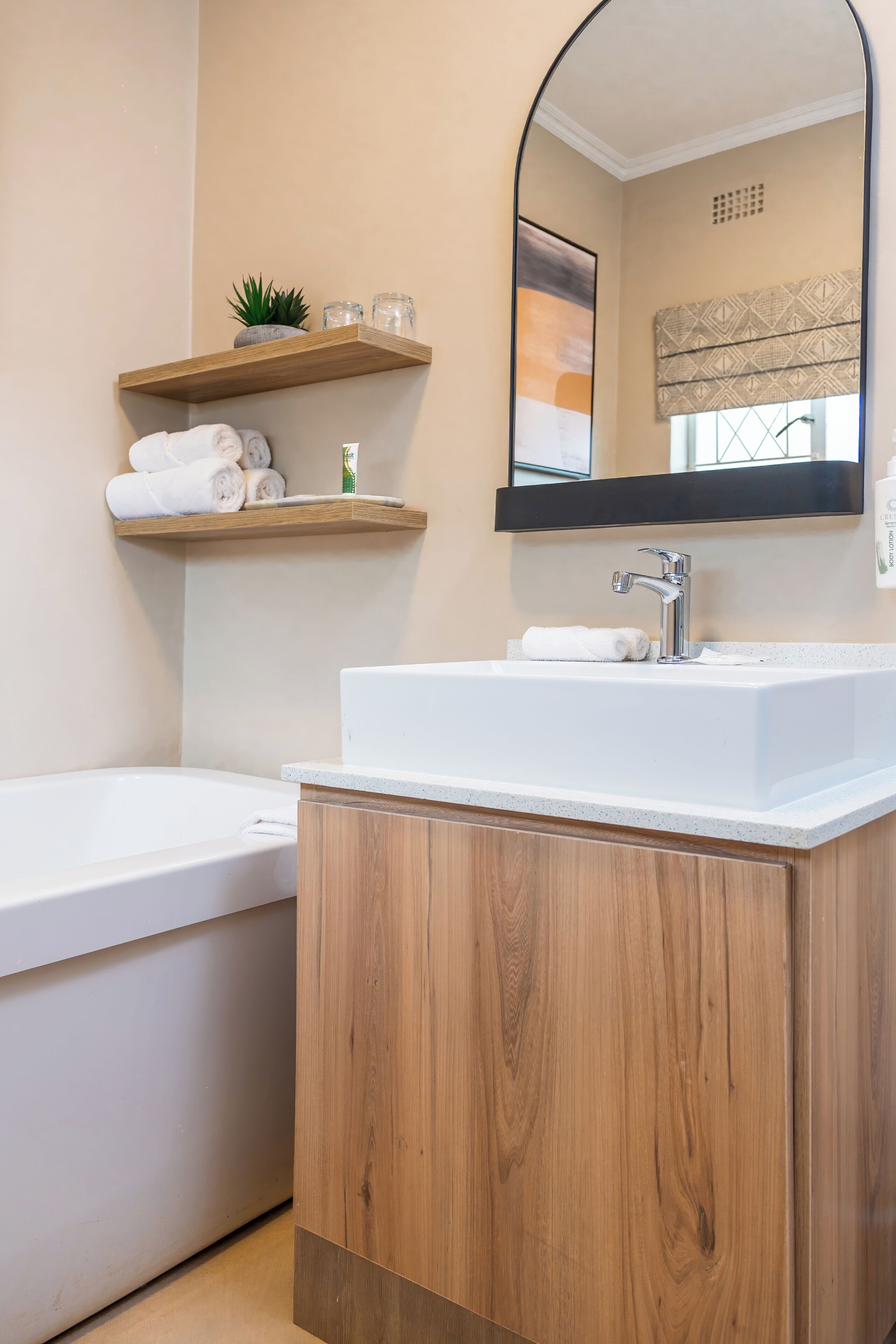 Une salle de bain moderne avec une baignoire sur pieds, un meuble-lavabo en bois et un miroir au-dessus du meuble.