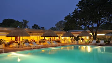 Una piscina al aire libre, sombrillas, sillones reclinables de piscina