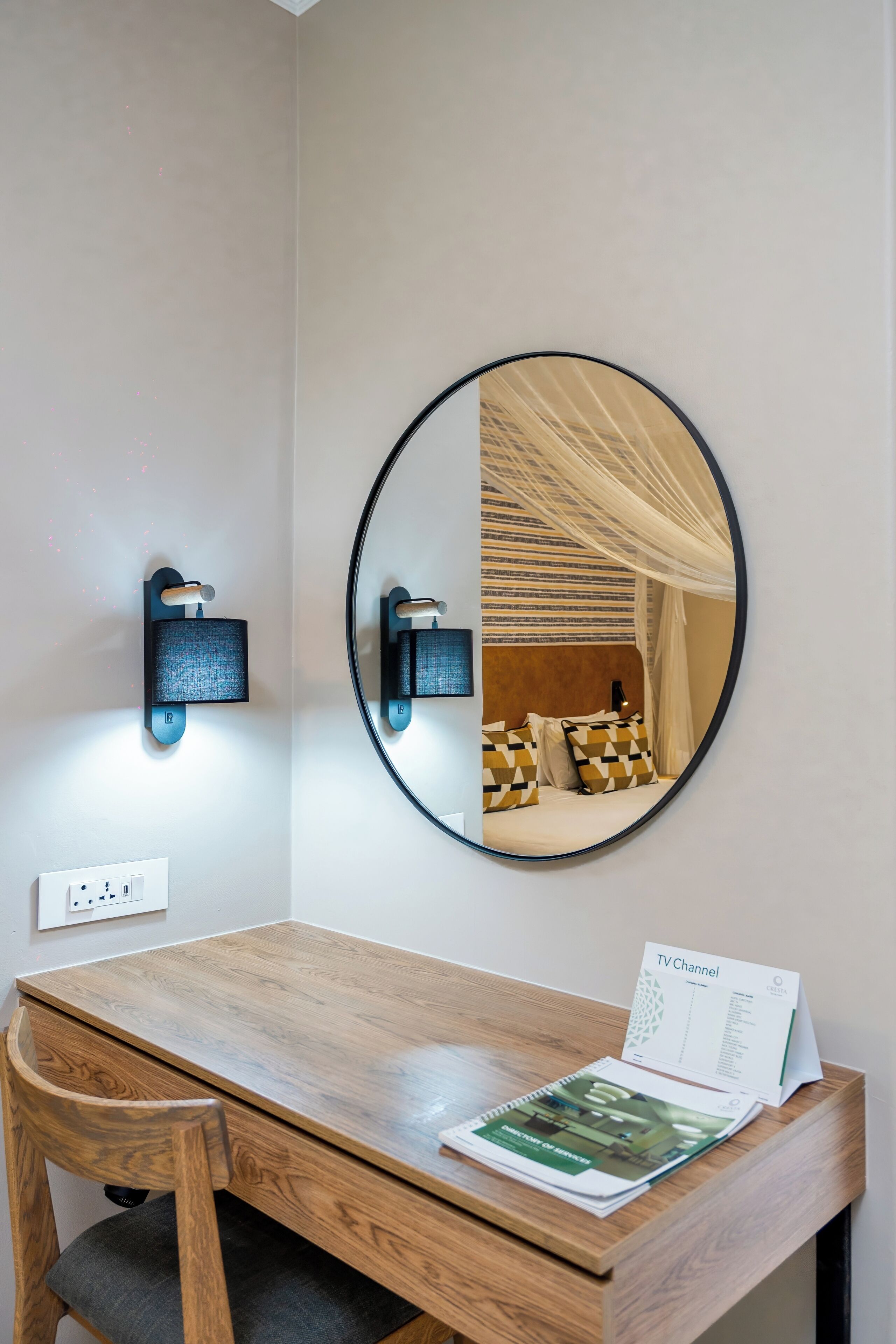 A hotel room with a wooden desk, a mirror, a TV channel sign, and a bed with a canopy.