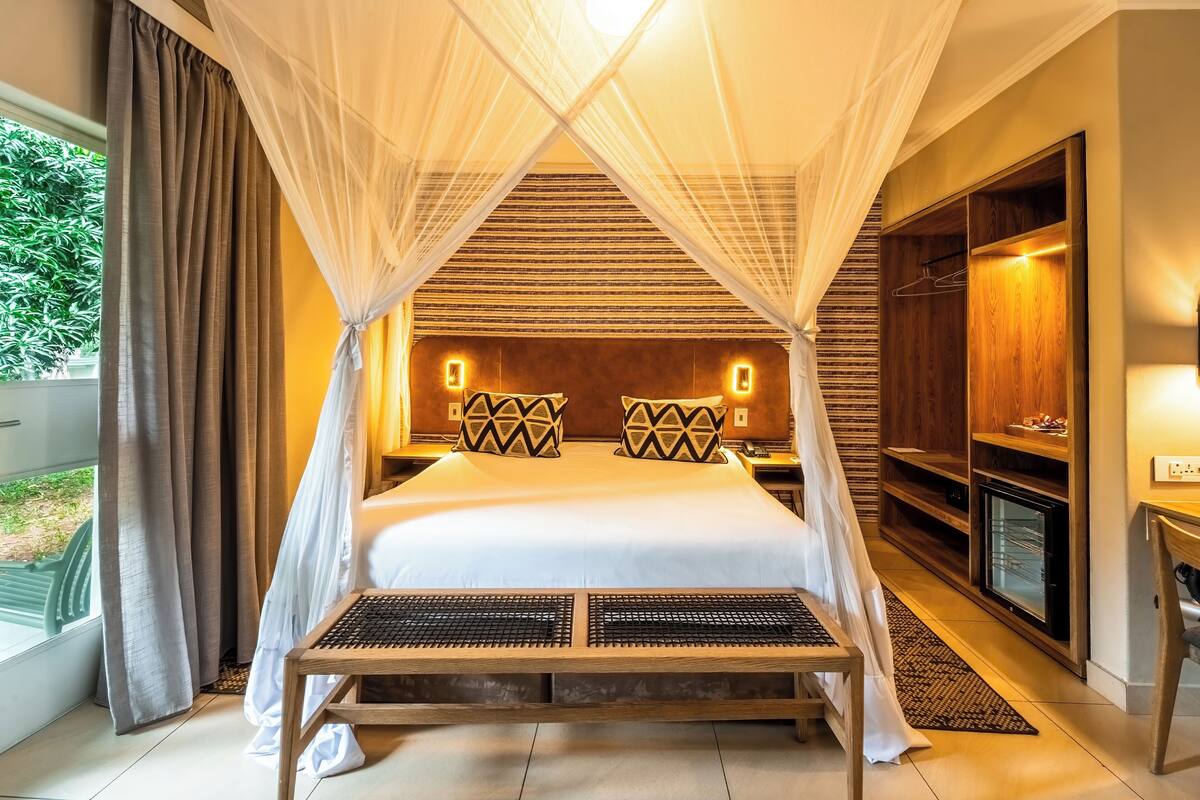 A room with a bed under a canopy, a television, and a wardrobe.