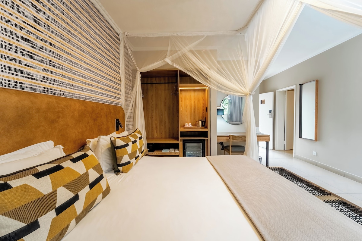 Une chambre d’hôtel avec un grand lit, une armoire, un bureau et un miroir.