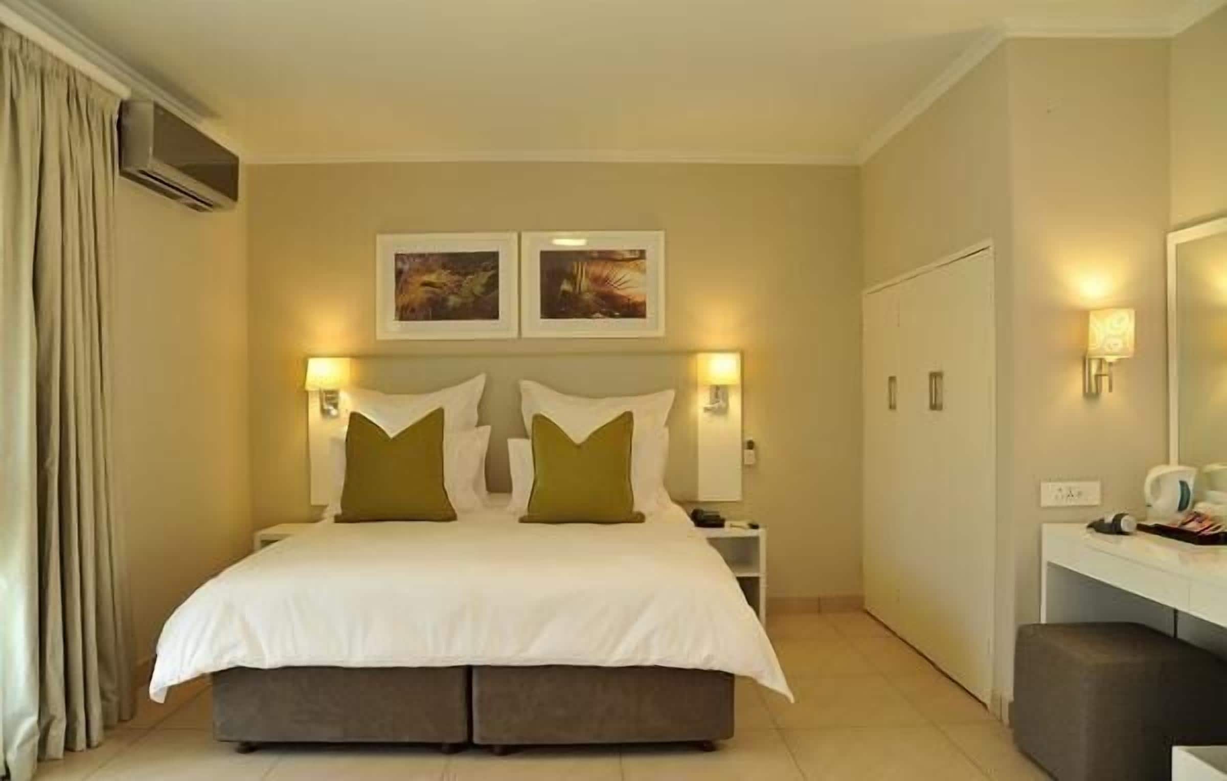 A hotel room with a large bed, two bedside tables, a desk, and a chair.