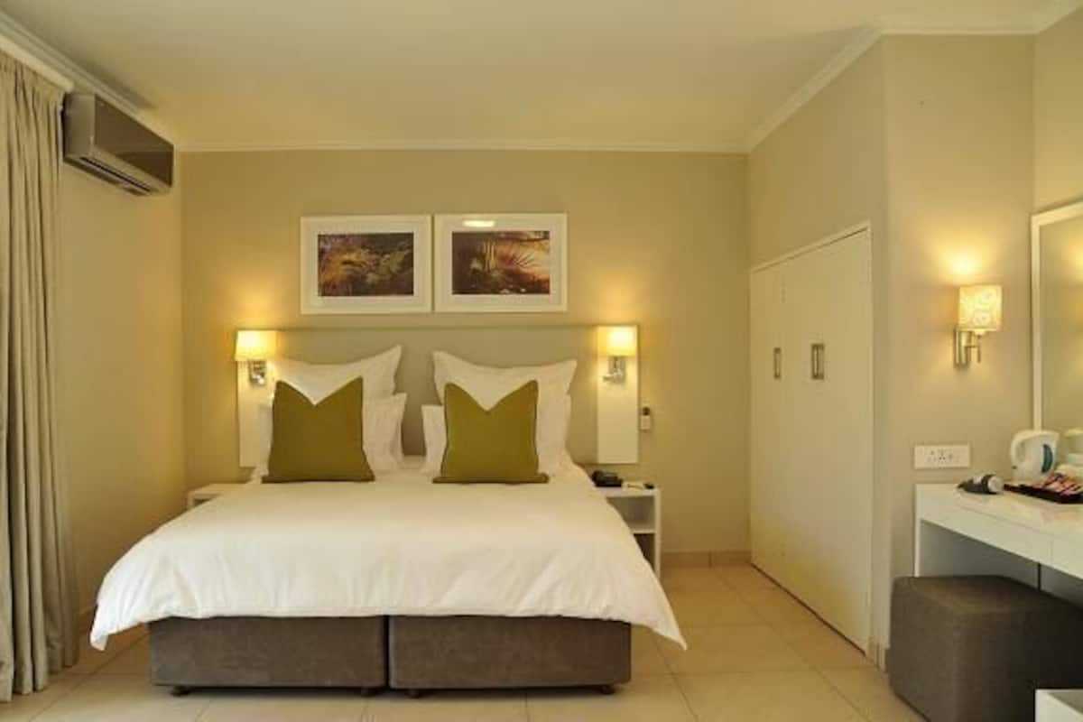 Une chambre d’hôtel avec un grand lit, deux tables de chevet, un bureau et une chaise.