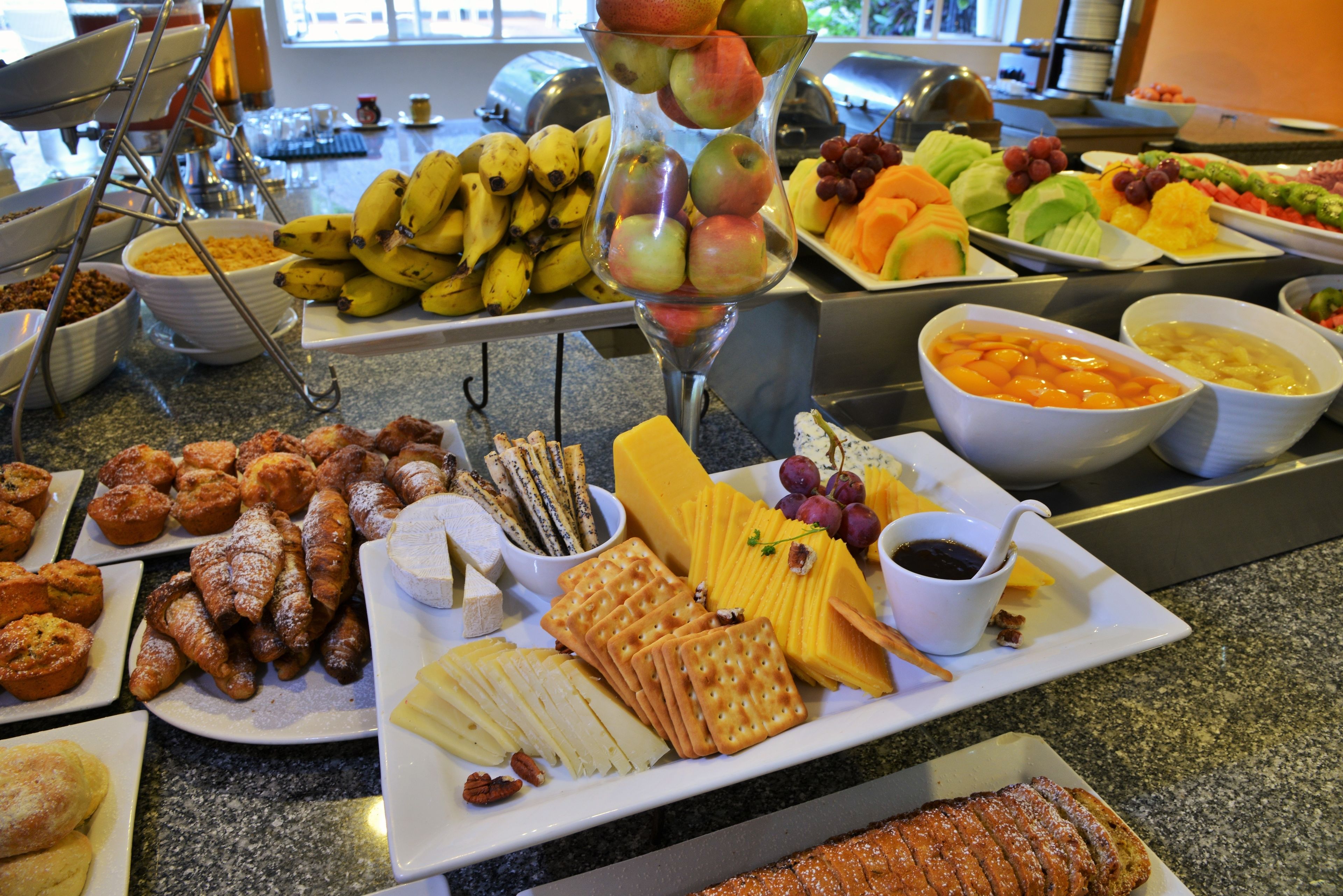 Un bufé con diversas opciones de comida, como frutas, quesos, pasteles y pan.