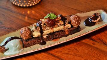 A dessert plate with various sweets and a chocolate-covered item on a wooden table.