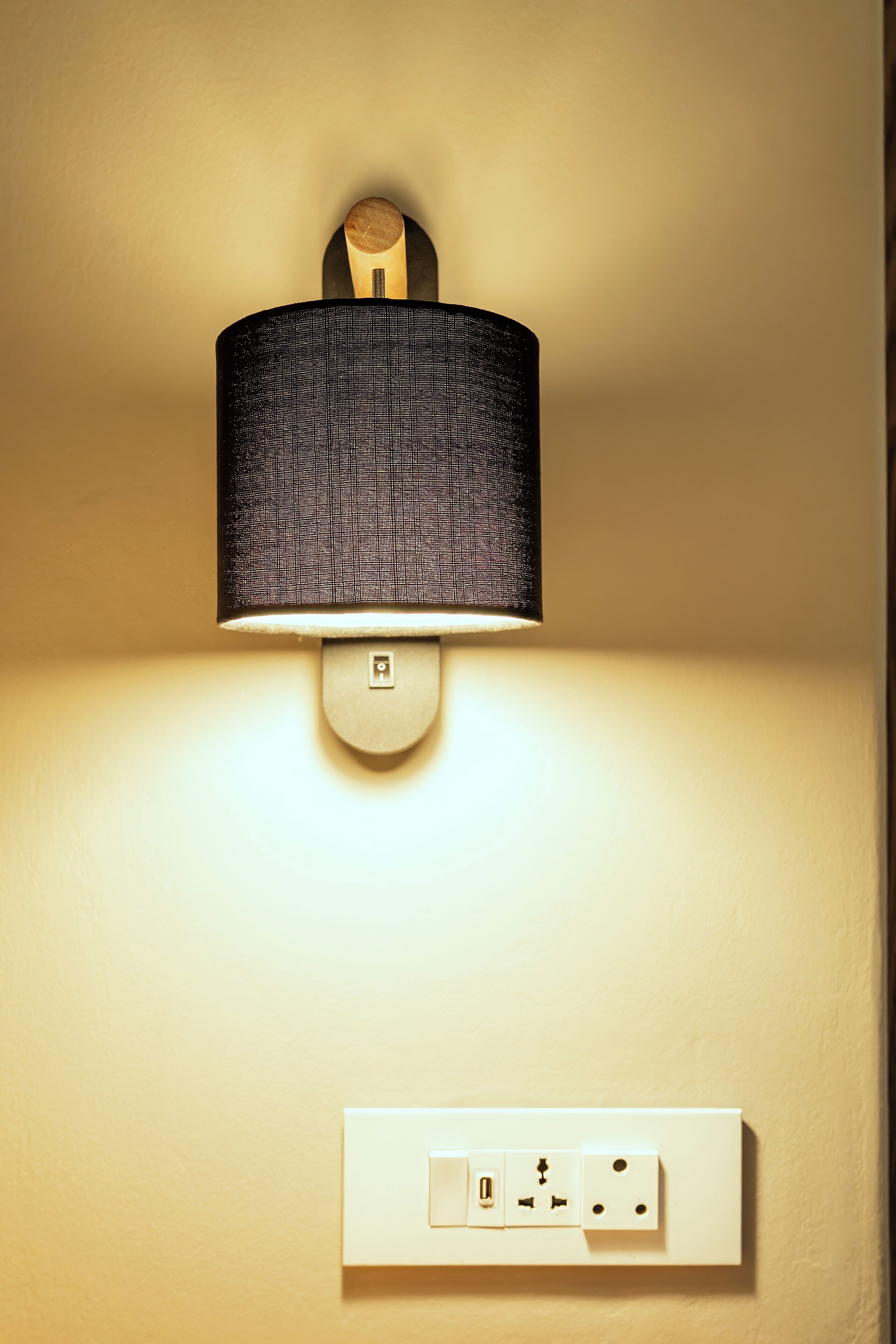 A wall-mounted lamp with a textured shade and a switch below it.