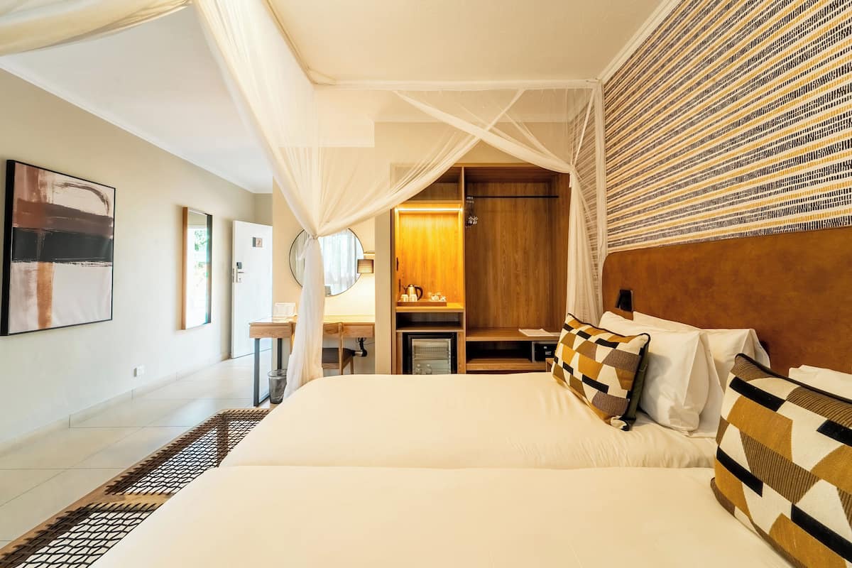 A spacious bedroom with a large bed, a bedside table, a mirror, and a wardrobe.