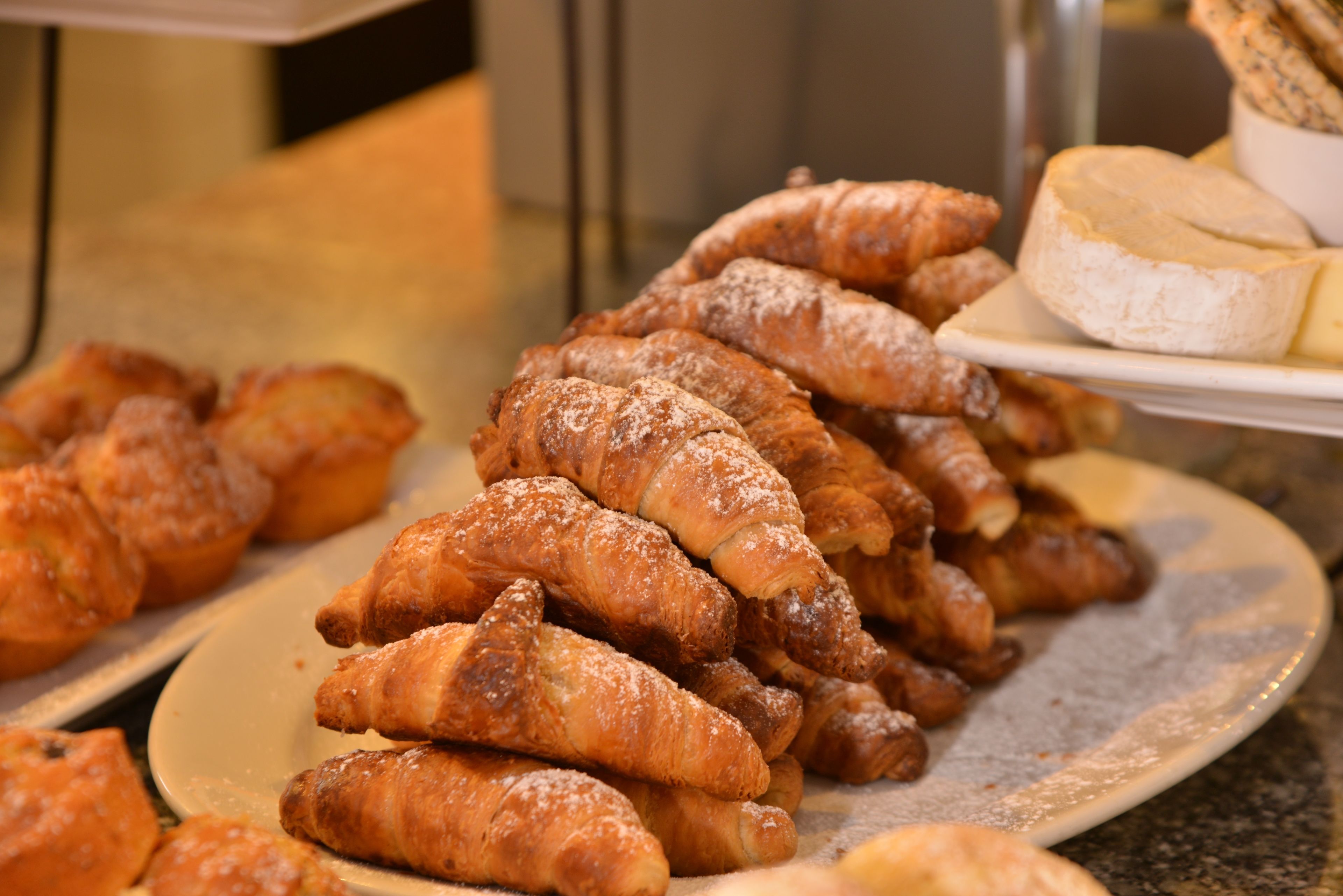 A variety of pastries including croissants and a plate of cheese.