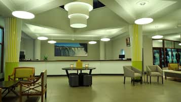 Eine Hotelhalle mit Empfangstresen, Sitzgelegenheiten und einem Wandbild mit einem Wasserfall.