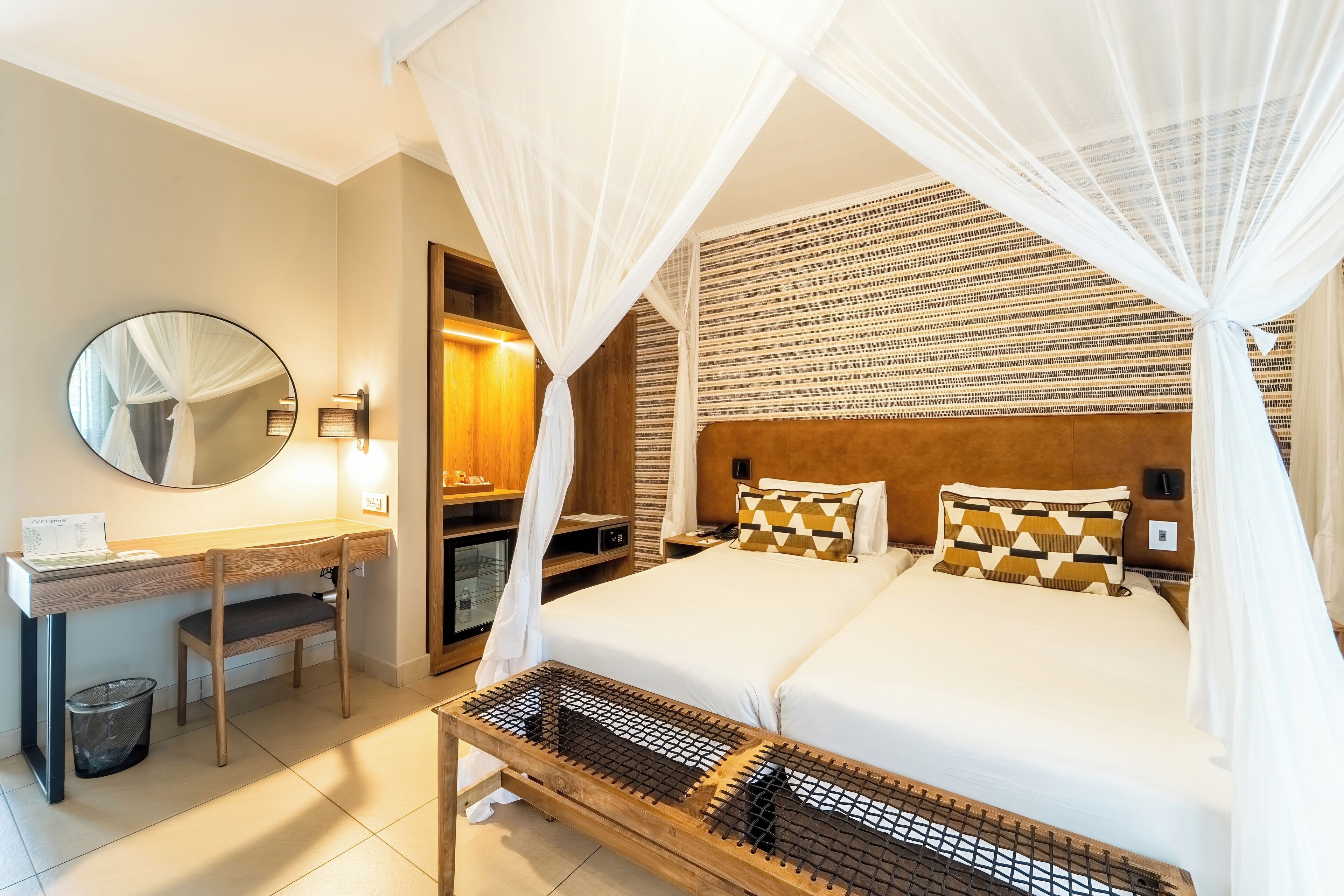 Habitación de hotel con cama, escritorio, silla, televisor y mesita de noche.