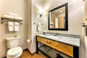 A modern bathroom with a toilet, sink, and mirror. There are towels on a rack and a tissue box on the sink. - Holiday Inn Express & Suites Houston East - Baytown by IHG (Baytown)