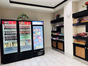 A vending area with multiple beverage dispensers and snack shelves. - Holiday Inn Express & Suites Houston East - Baytown by IHG (Baytown)