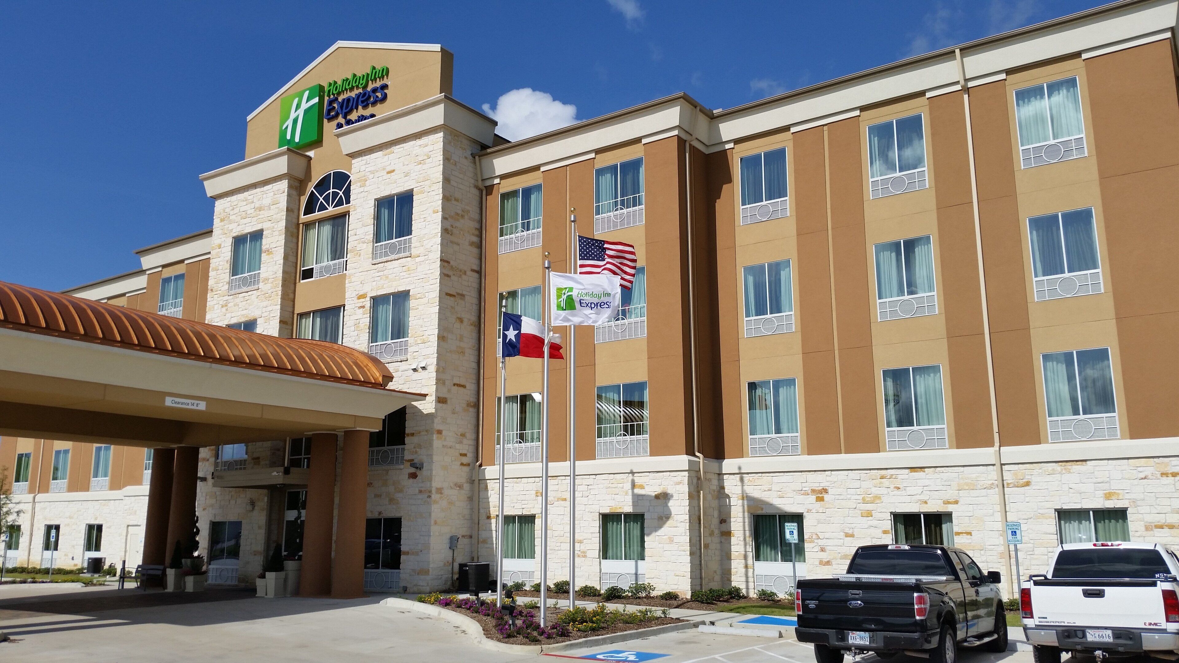 A Holiday Inn Express building with a stone facade, multiple windows, and flags.