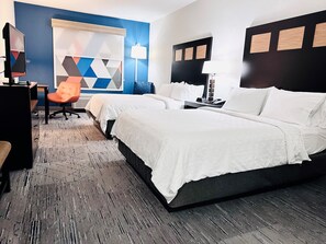 A hotel room with a large bed, a desk with a chair, a TV, and a wall with geometric patterns. - Holiday Inn Express & Suites Houston East - Baytown by IHG (Baytown)