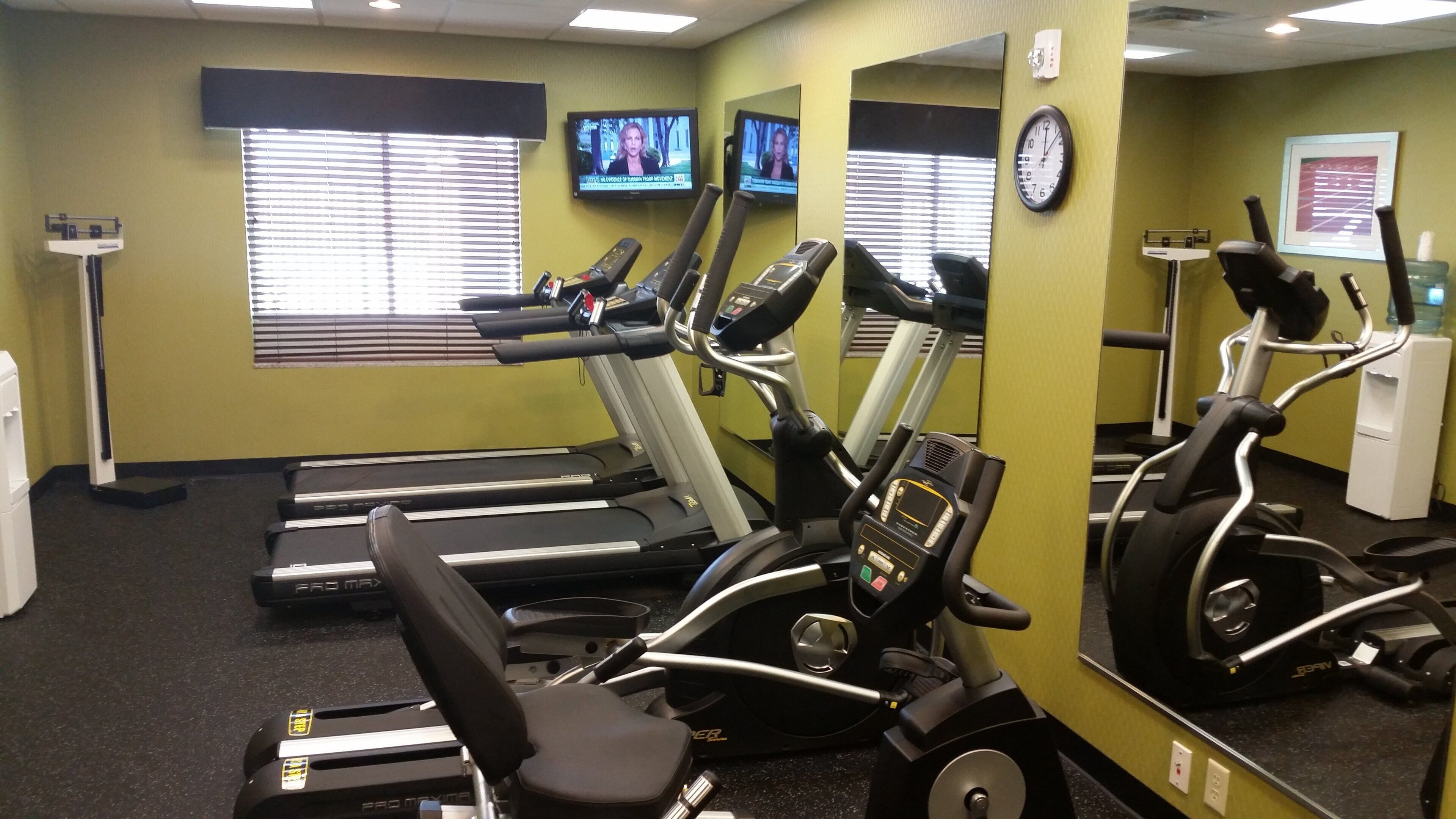 A gym with treadmills, elliptical machines, and a water dispenser.