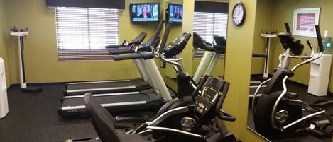 A gym with treadmills, elliptical machines, and a water dispenser.