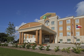 A Holiday Inn Express building with a covered entrance, multiple windows, and flags. - Holiday Inn Express & Suites Houston East - Baytown by IHG (Baytown)