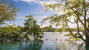 On peut voir clairement un lac, avec des arbres et une jetée qui s’avance dans l’eau.