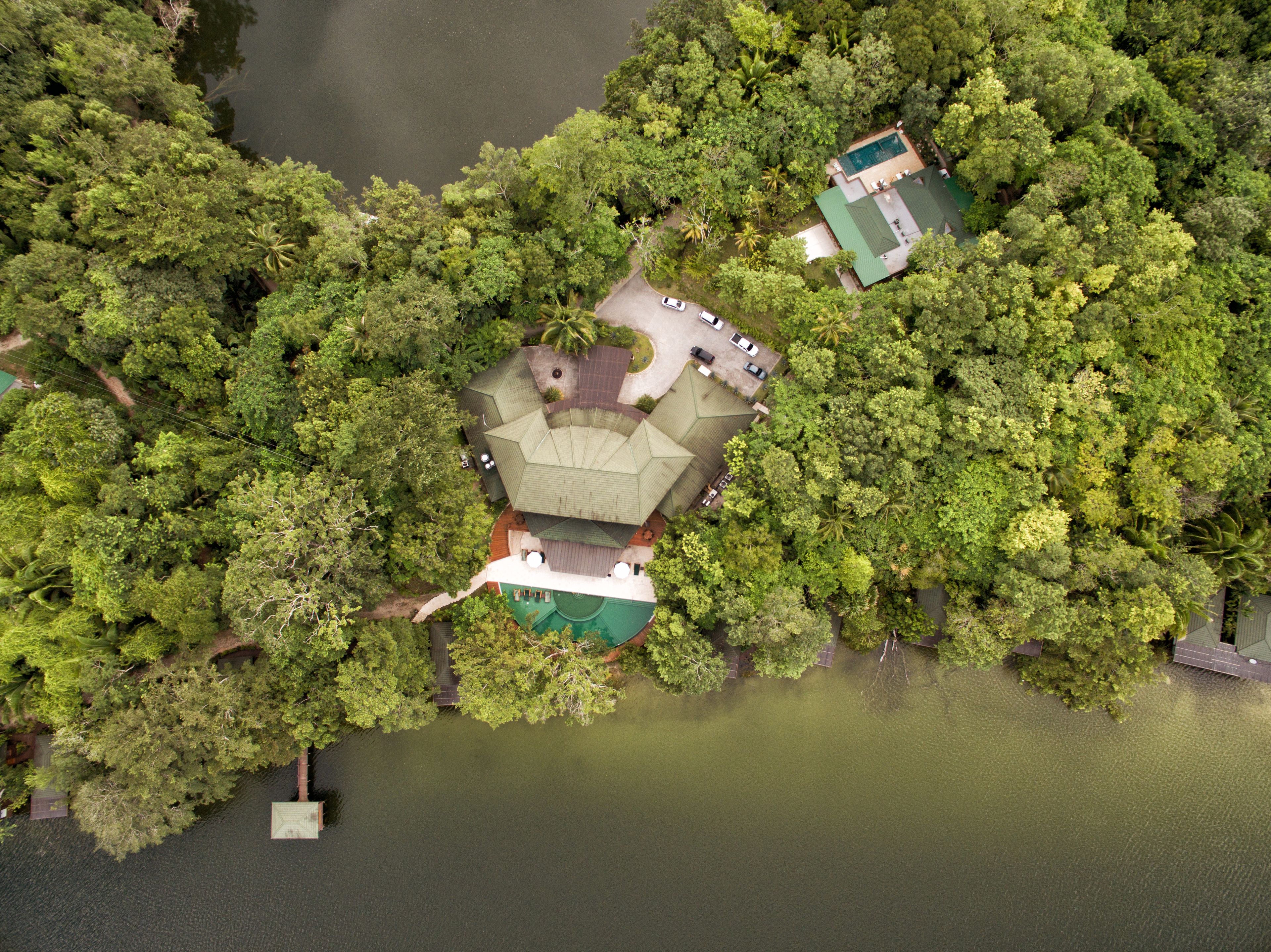 Ein Luftbild zeigt ein Resort mit einem zentralen Gebäude, umgeben von dichter Vegetation und einem See.