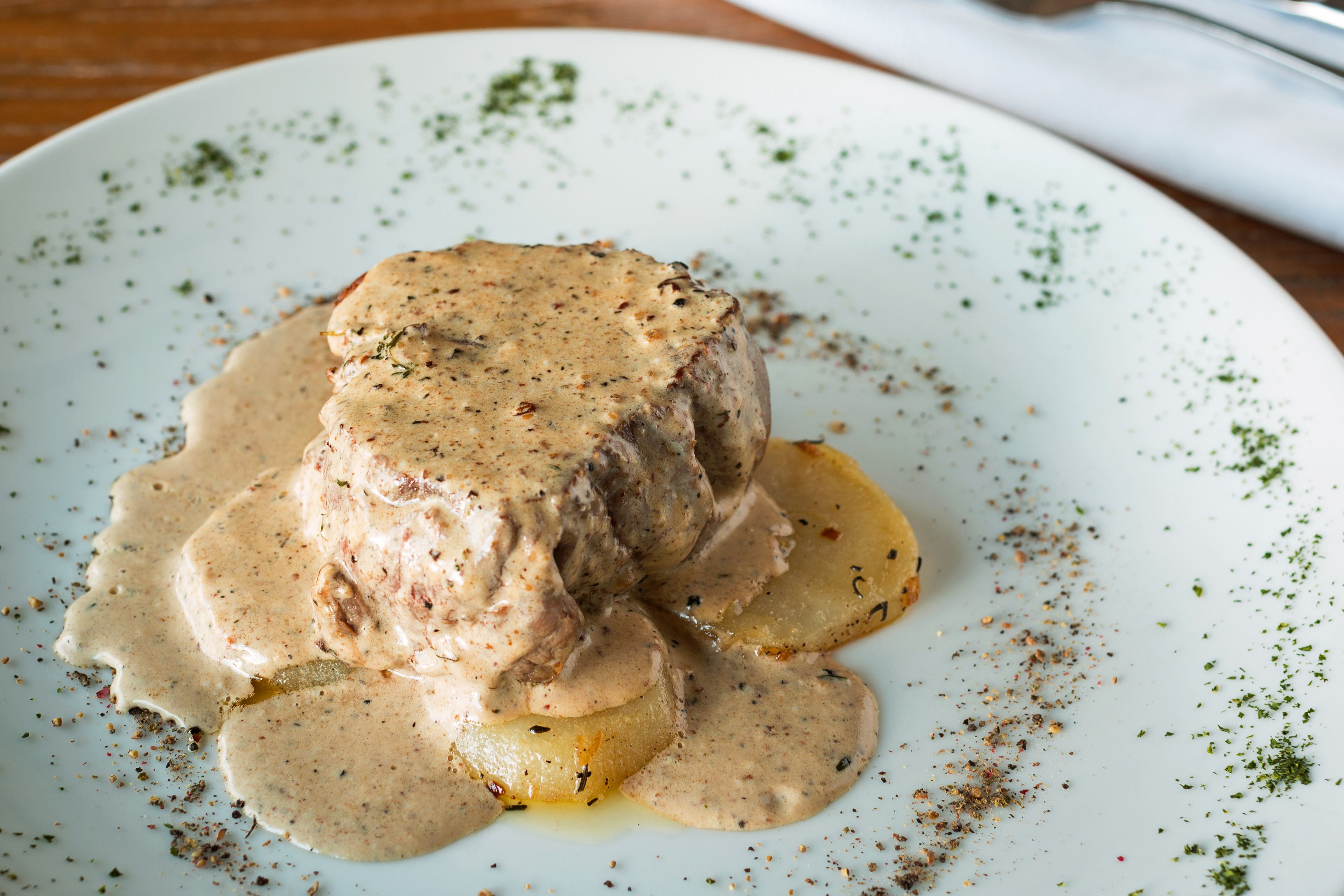 A plate with a meat dish and sauce, garnished with herbs.