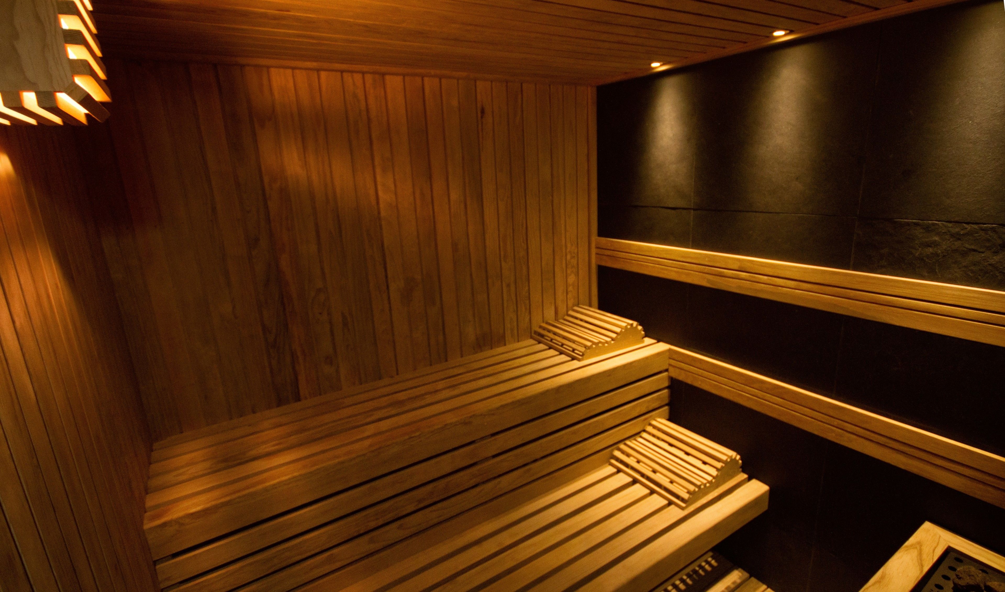 A sauna with wooden benches and a dark wall.