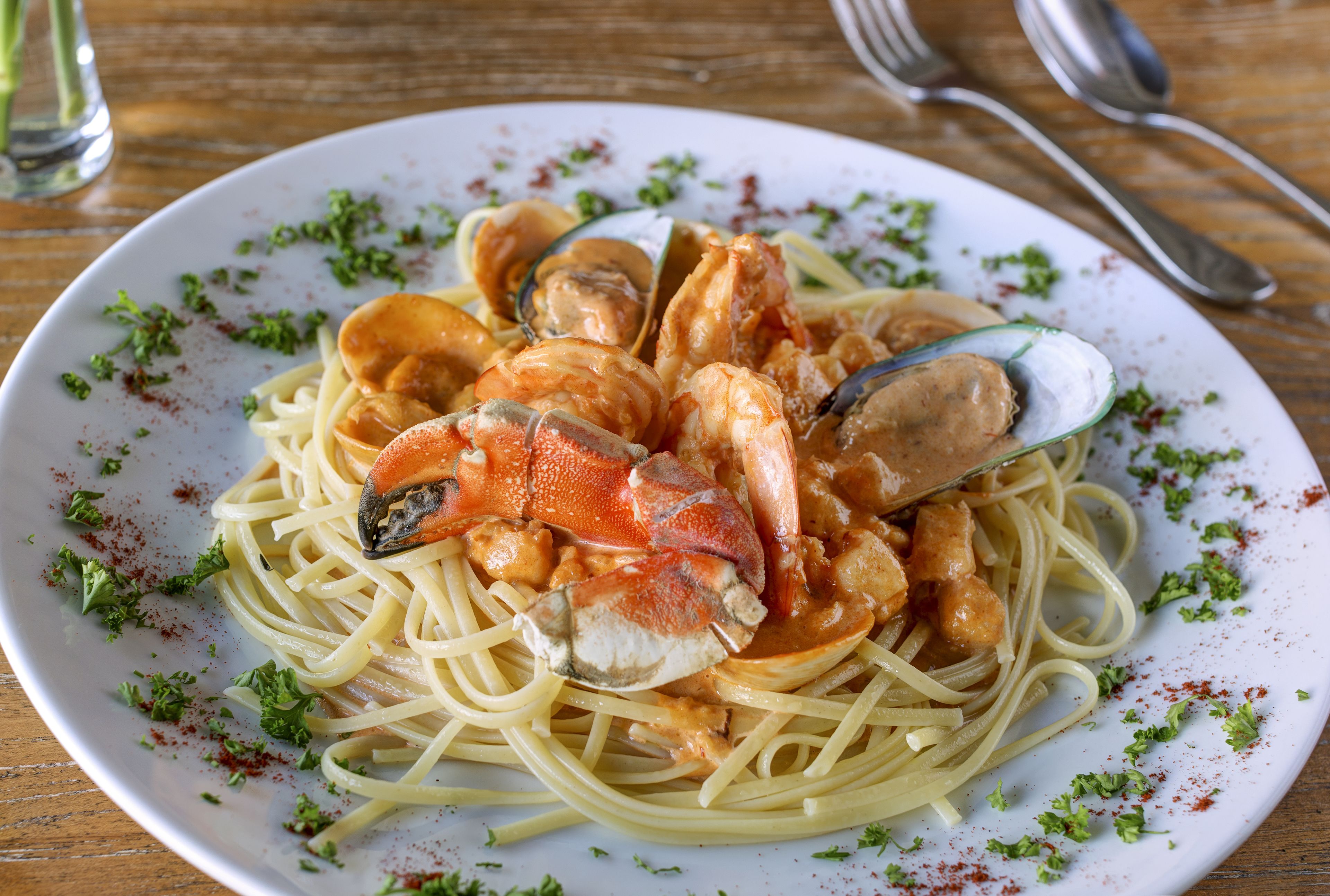 A plate of spaghetti with clams and shrimp, garnished with herbs.