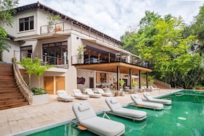 Une maison moderne à deux étages, dotée d’une piscine, d’un espace extérieur aménagé et d’un escalier.