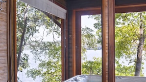 Une cabane en bois avec un bain à remous, une douche et une vue sur un lac.