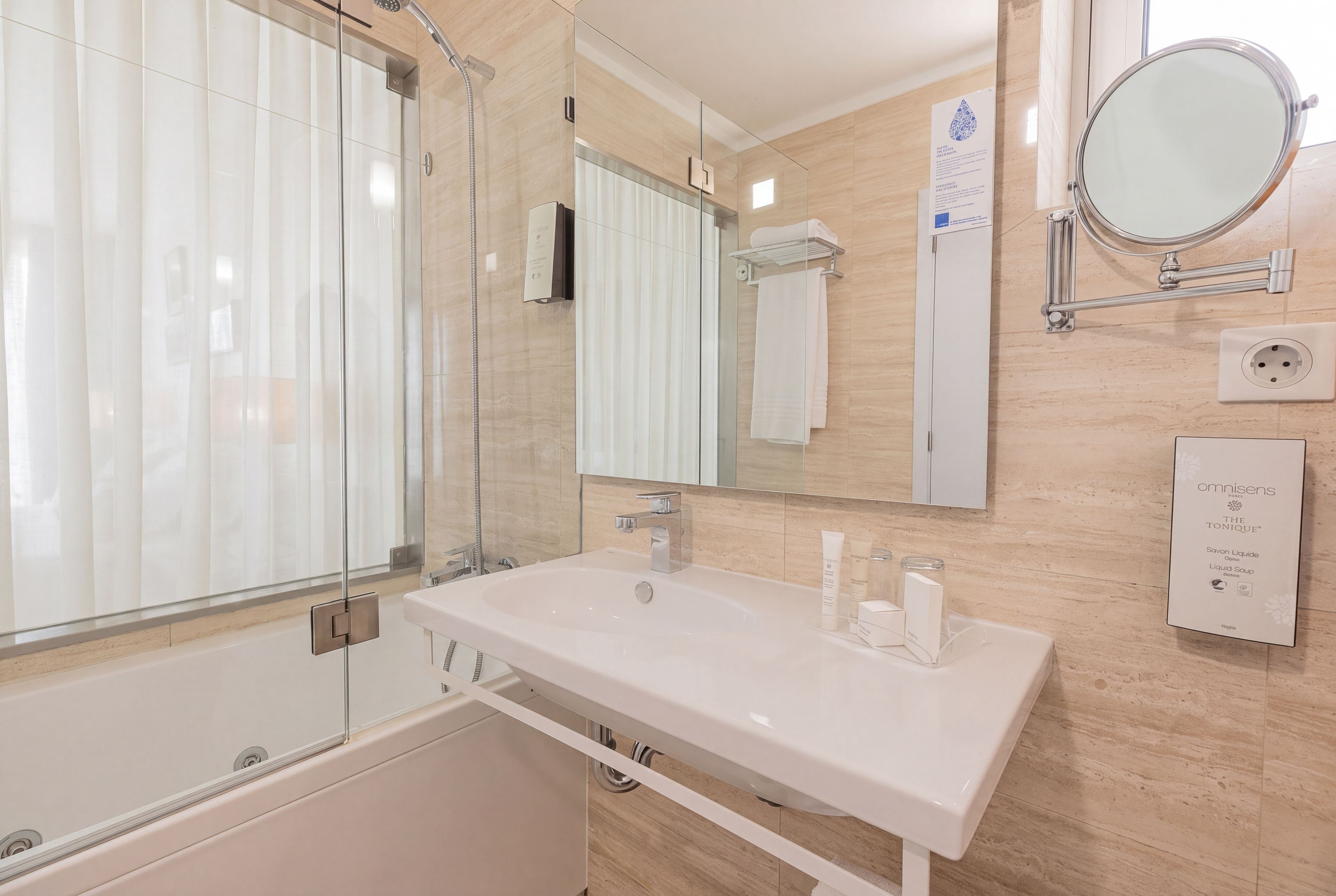A modern bathroom with a glass shower enclosure, a white sink, and a large mirror.