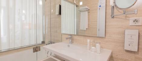 A modern bathroom with a glass shower enclosure, a white sink, and a large mirror.