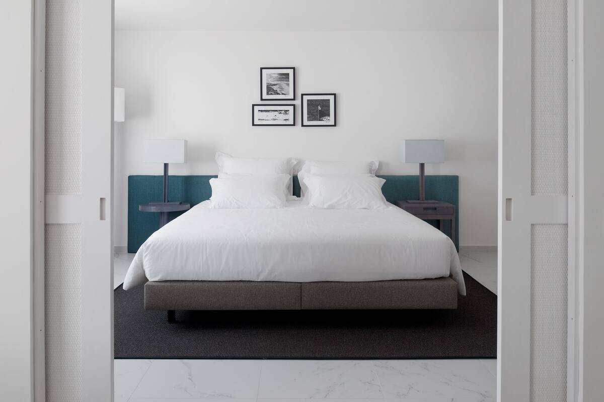 Una habitación de hotel moderna con una cama grande, dos mesitas de noche y dos lámparas de pared.