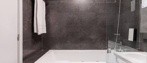 A modern bathroom with a bathtub, a shower, and a sink.