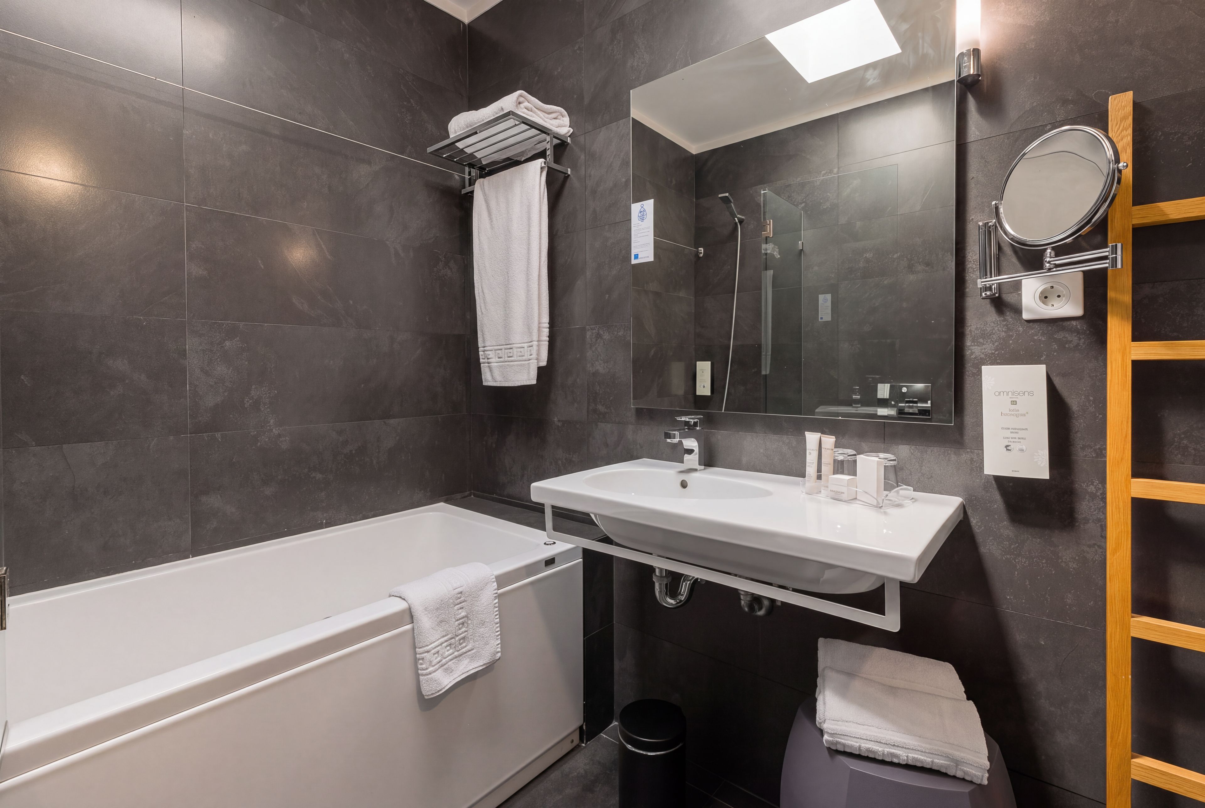 Un baño moderno con bañera, lavamanos, espejo y perchero.