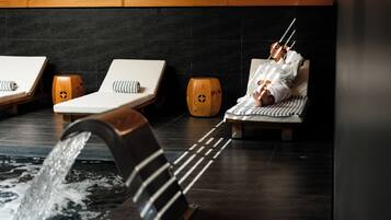 A spa area with three lounge chairs, a wooden bench, and a water feature.