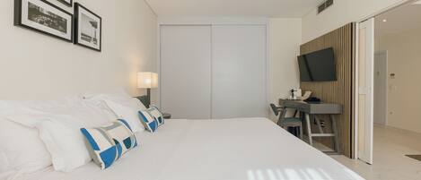 Una habitación de hotel con una cama grande, un escritorio, un televisor y un armario.