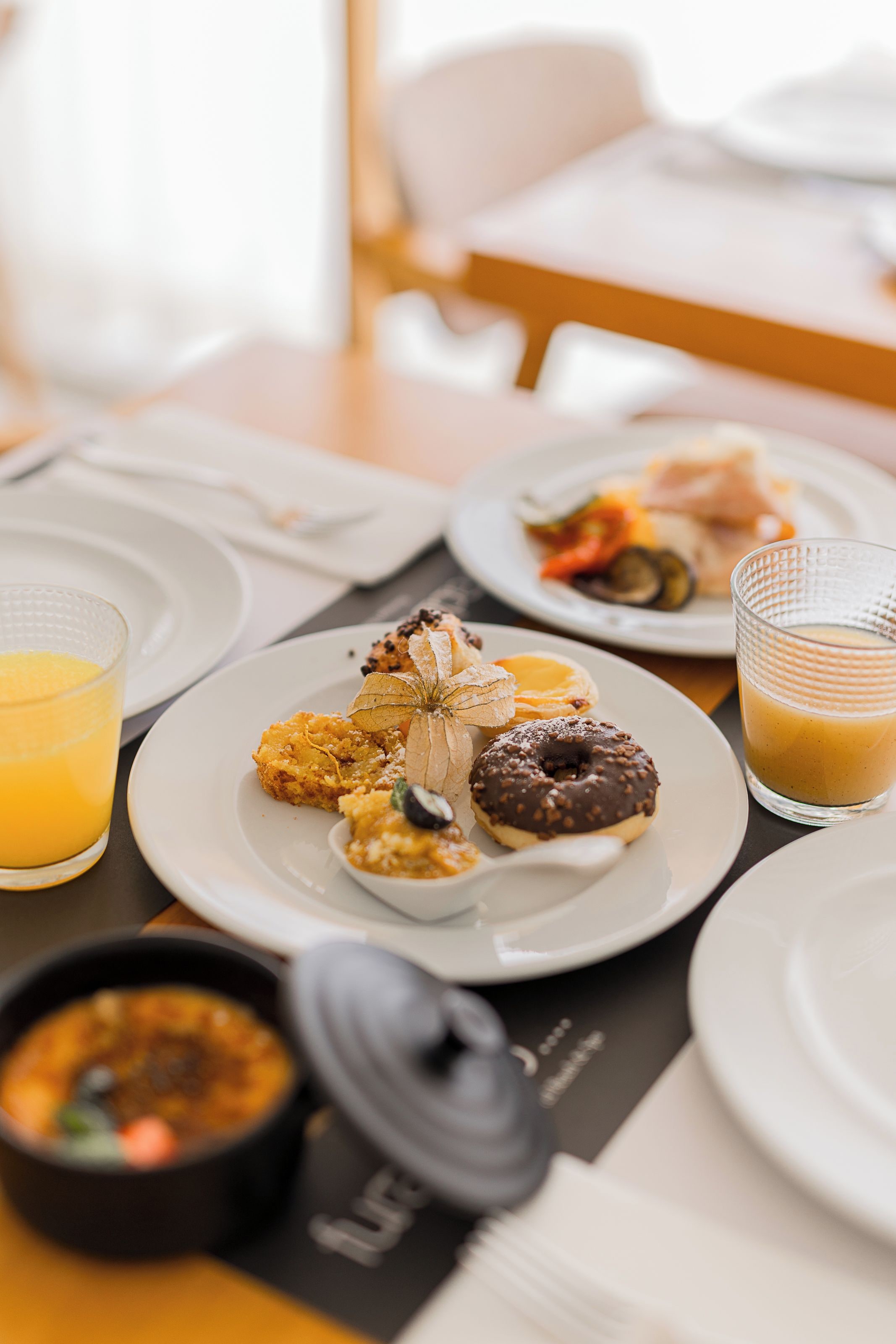 Un desayuno con platos de comida, un vaso de jugo de naranja y un tazón de sopa.