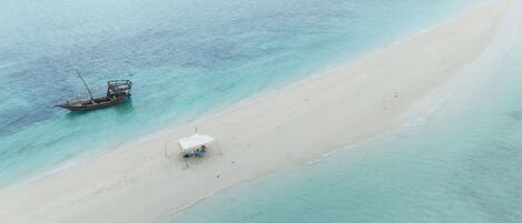 Luchtbeeld van een strand met een boot en een kleine tent.