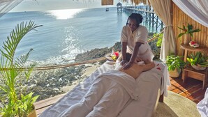 A massage room with a view of the ocean and a pier. - Zanzi Resort (Kama)