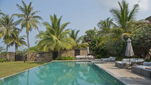 Una piscina con sillones de descanso y una pared de piedra.