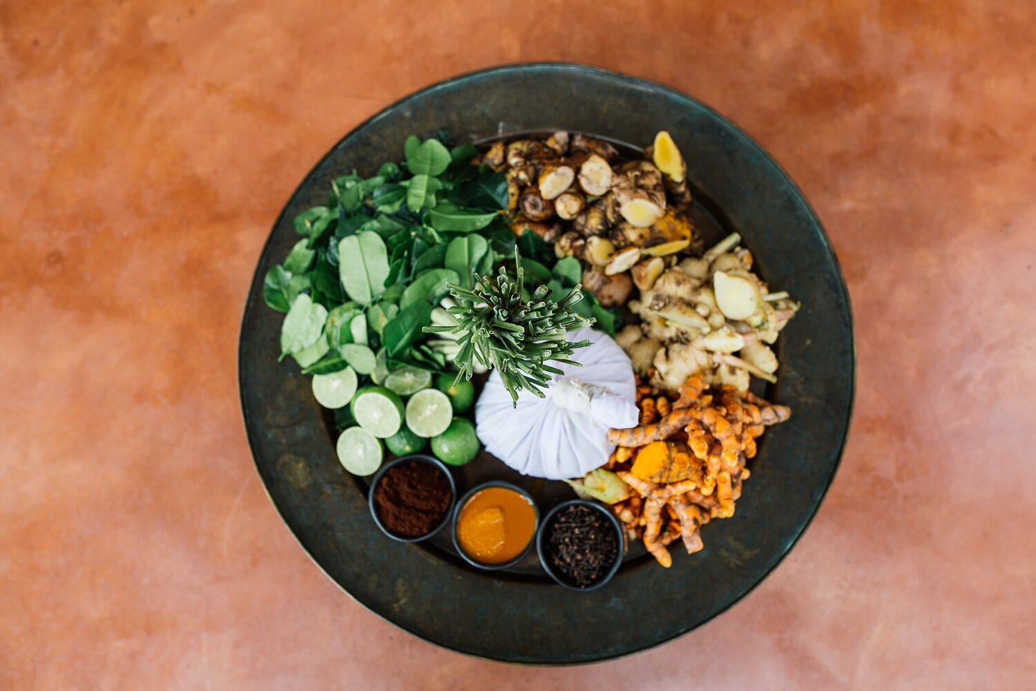 A plate with various food items including greens, garlic, ginger, and spices.
