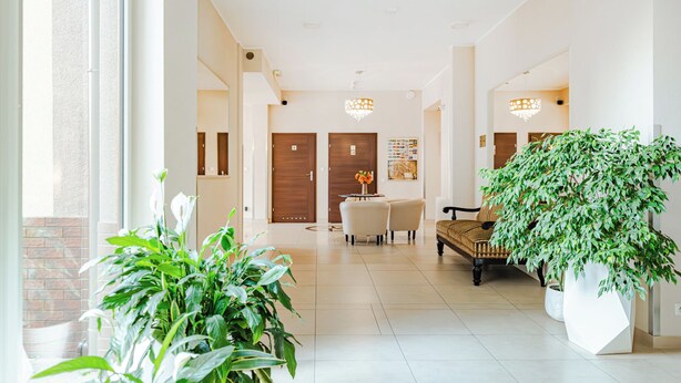A hotel lobby with a reception desk, seating area, and potted plants. - Hotel Sleep Wroclaw (Wroclaw)