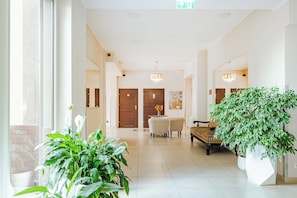 Un hall de hotel con mostrador de recepción, zona de estar y plantas en macetas.