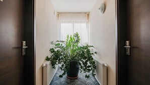 A hallway with a potted plant, a radiator, and a window with curtains. - Hotel Sleep Wroclaw (Wroclaw)