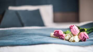 A bed with a blue blanket and a bouquet of pink and white tulips.