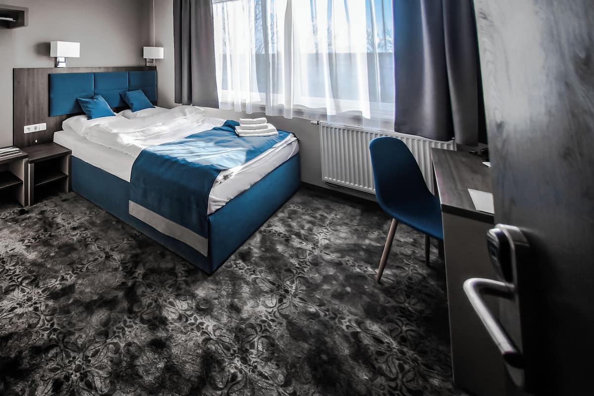 Ett modernt hotellrum med en stor säng, ett skrivbord, en stol och utsikt över omgivningarna.