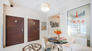 A hotel lobby with two wooden doors, a round table with books and a vase of flowers, and a large window displaying the hotel's name and logo. - Hotel Sleep Wroclaw (Wroclaw)